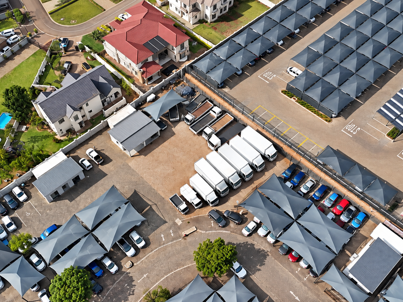 Aerial view of a commercial office property featuring extensive paved parking areas with shade cloth carports and well-maintained surrounding grounds.