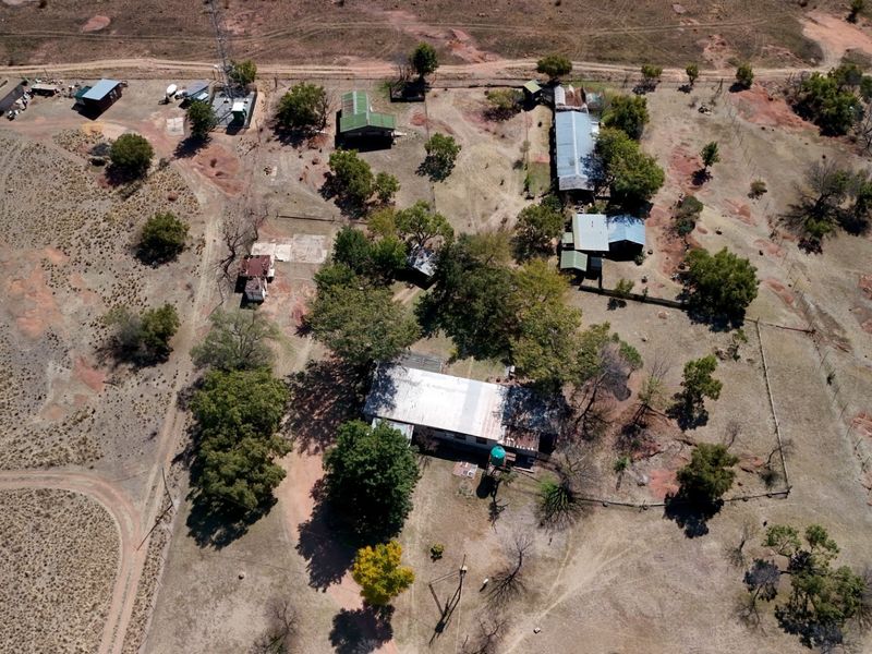 Aerial view of a large vacant commercial land plot featuring multiple outbuildings, perimeter fencing, and existing infrastructure including a telecommunications mast.