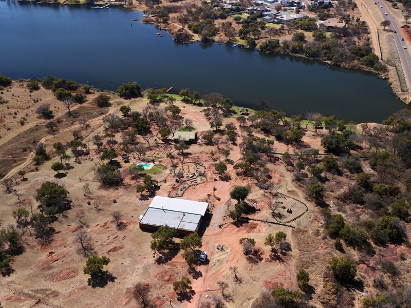 Aerial view of a large commercial vacant land plot featuring a main structure, swimming pool, and direct access to a riverfront.