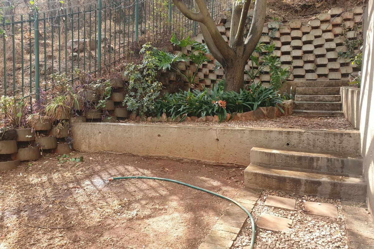 A terraced rear garden area featuring concrete retaining walls, stone steps, and established landscaping, providing a functional outdoor space.