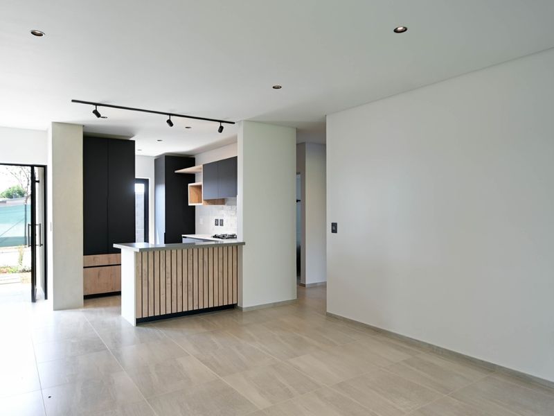Modern open-plan living area featuring a contemporary kitchen with sleek cabinetry, a breakfast island, and neutral tiled flooring throughout.
