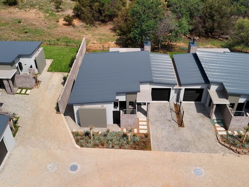 Aerial view of modern retirement village units featuring metal roofing, paved driveways, and landscaped garden areas.