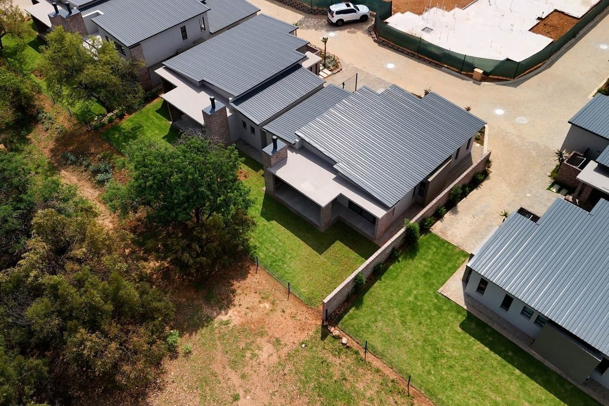 Aerial view of modern retirement village units featuring metal roofing, covered patios, and well-maintained private garden spaces.