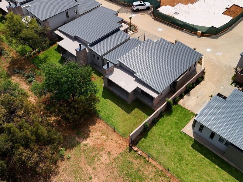 Aerial view of modern retirement village units featuring metal roofing, covered patios, and well-maintained private garden spaces.