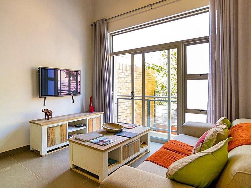 A bright living room featuring large sliding glass doors that open onto a balcony, providing ample natural light and access to outdoor space.