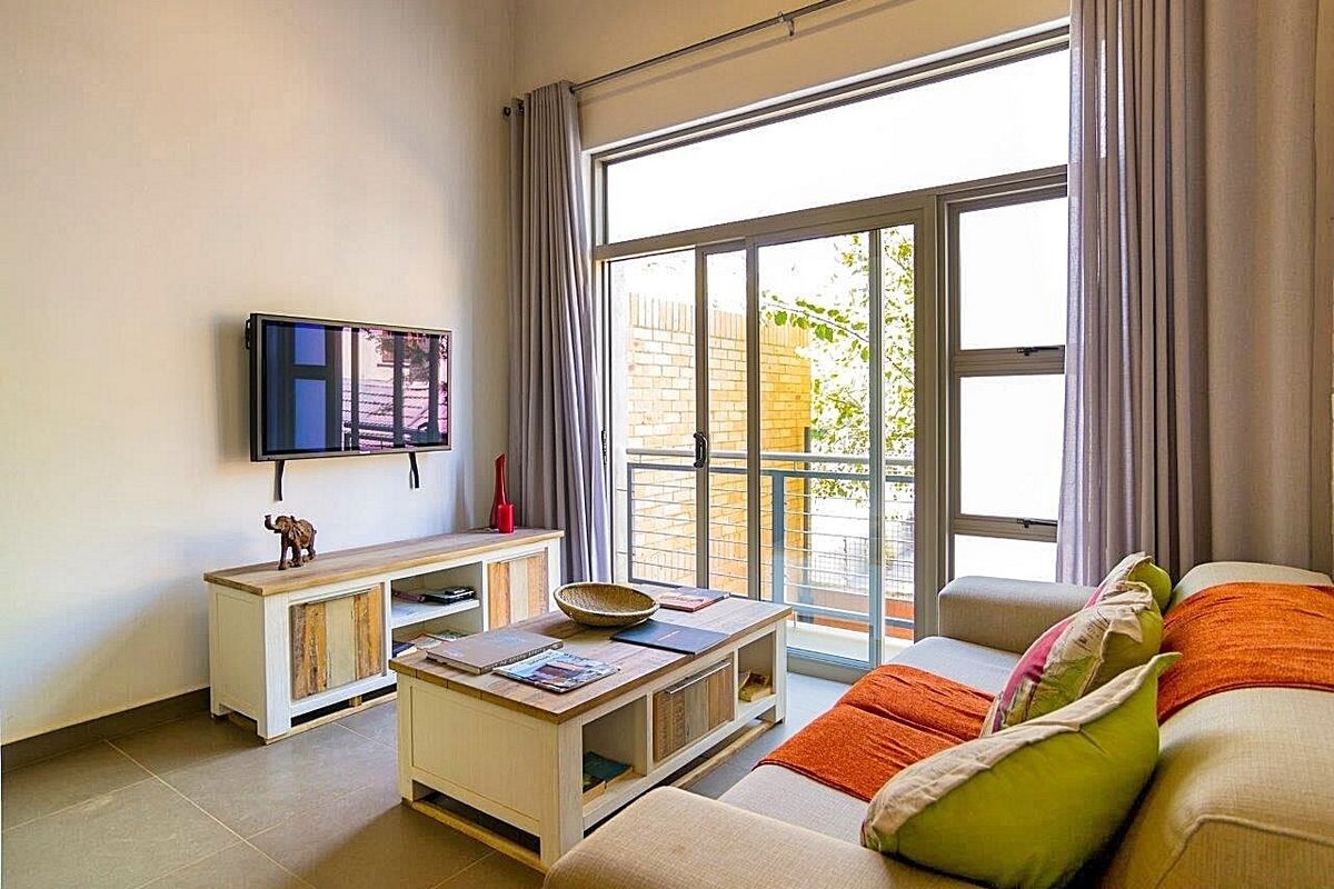 A bright living room featuring large sliding glass doors that open onto a balcony, providing ample natural light and access to outdoor space.