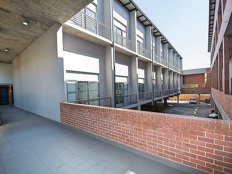 Exterior view of an apartment complex featuring a covered walkway, brick architectural details, and access to a paved parking area.