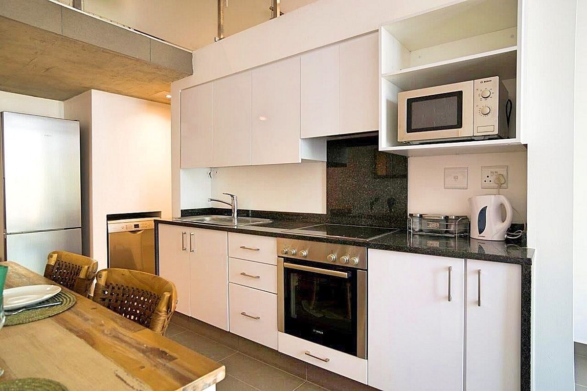 Modern kitchen featuring sleek white cabinetry, granite countertops, integrated stainless steel appliances, and a functional layout with ample storage space.