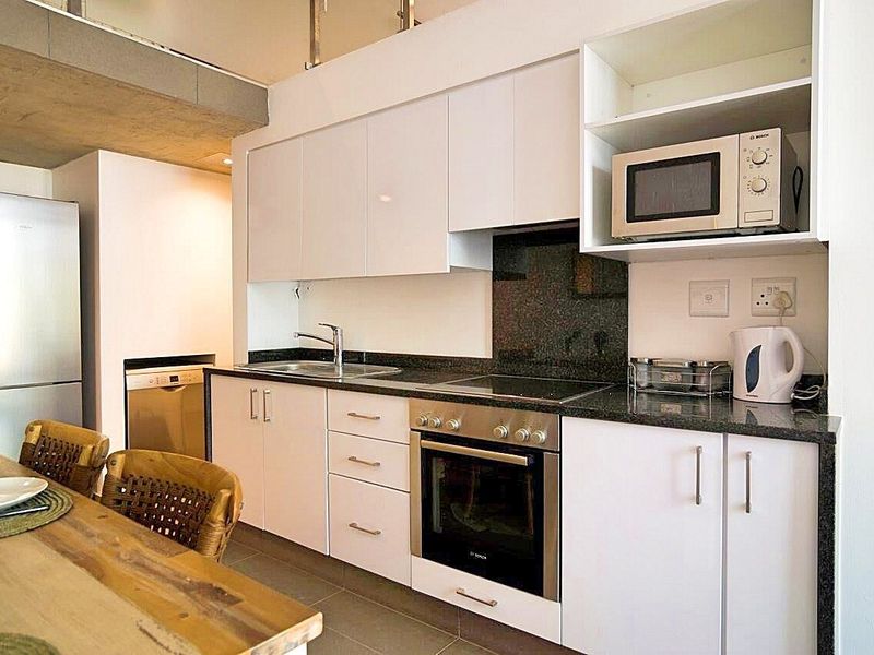 Modern kitchen featuring sleek white cabinetry, granite countertops, integrated stainless steel appliances, and a functional layout with ample storage space.