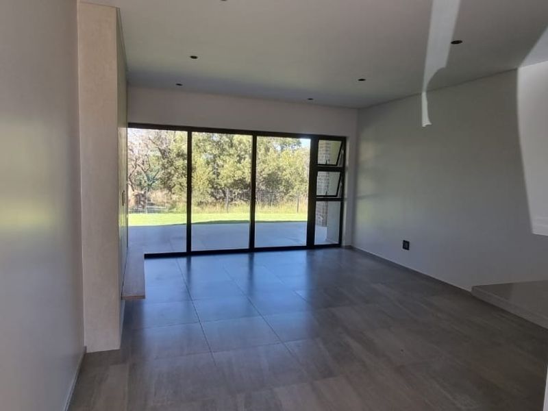 Spacious open-plan living area featuring large format floor tiles, recessed lighting, and sliding glass doors leading to an outdoor space.