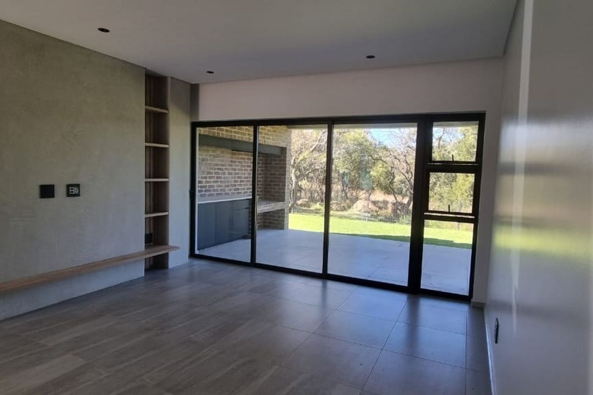 Spacious, modern living area featuring a textured feature wall, built-in shelving, and large sliding doors opening onto a covered patio.
