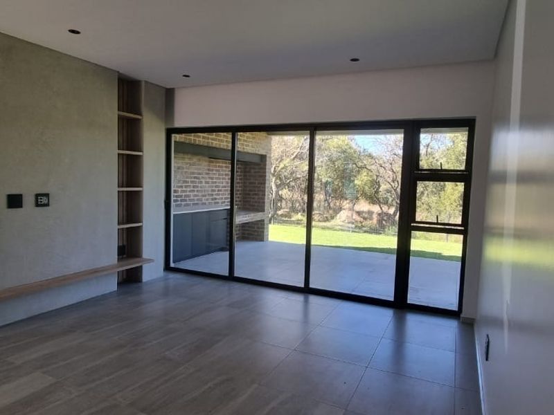 Spacious, modern living area featuring a textured feature wall, built-in shelving, and large sliding doors opening onto a covered patio.