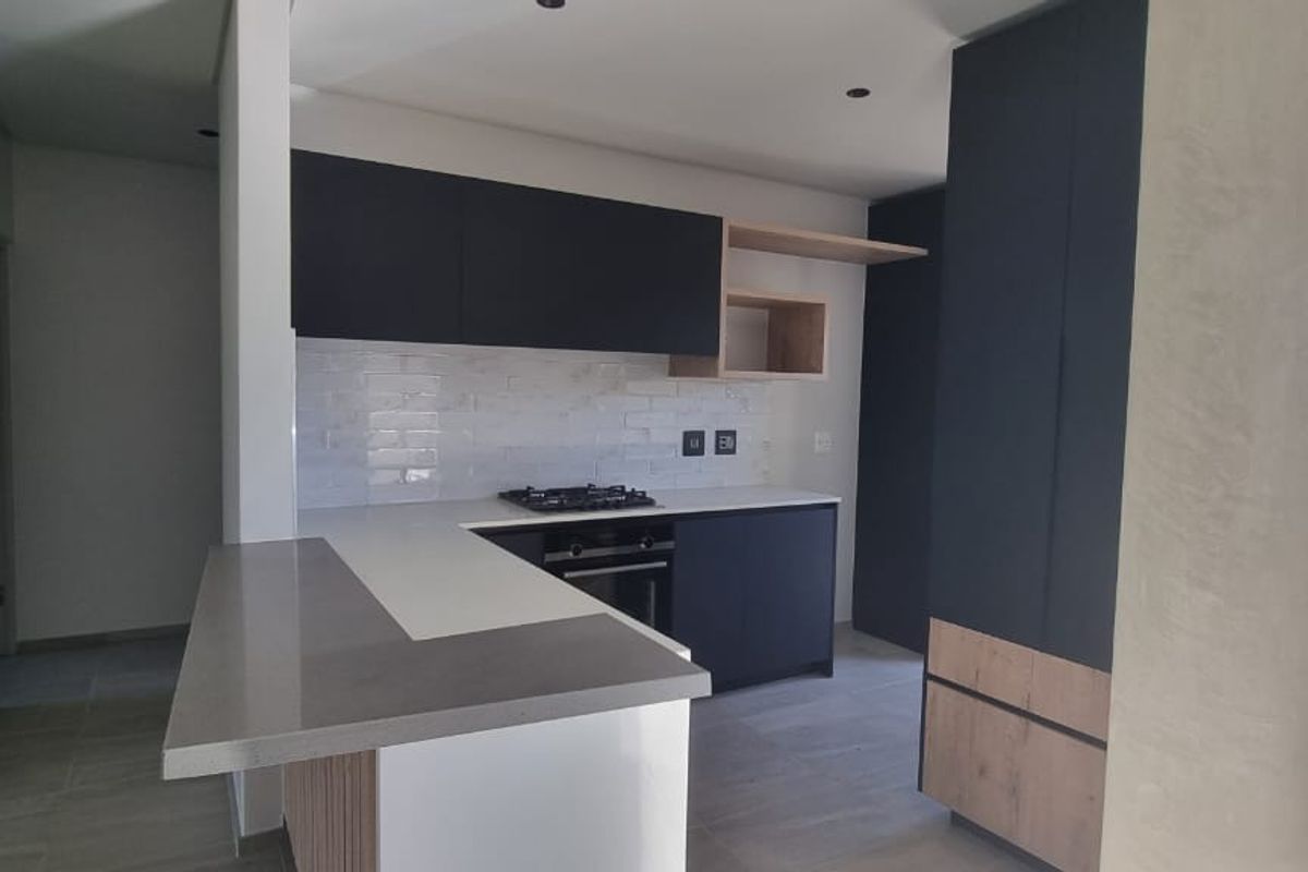 Modern kitchen featuring dark cabinetry, light wood accents, quartz countertops, a gas hob, and a subway tile backsplash in an open-plan layout.