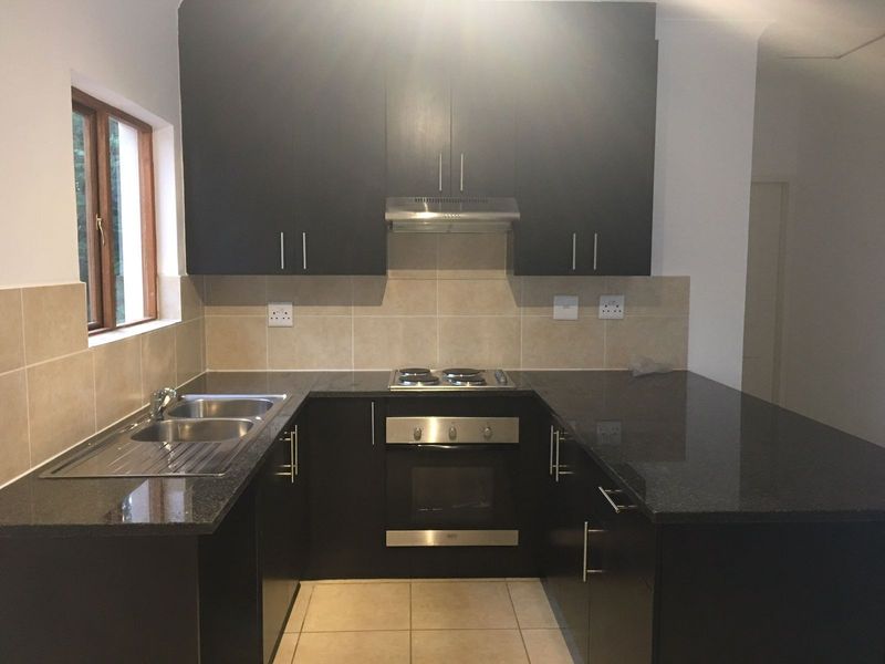 A modern, well-maintained kitchen featuring dark cabinetry, granite countertops, stainless steel appliances, and a tiled backsplash.