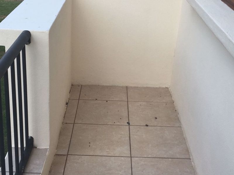 A compact balcony featuring tiled flooring and a metal balustrade, offering a simple outdoor space for the apartment.