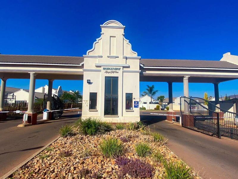 The secure entrance gatehouse of Morgenhof estate, featuring architectural columns, automated boom gates, and landscaped stone garden beds.