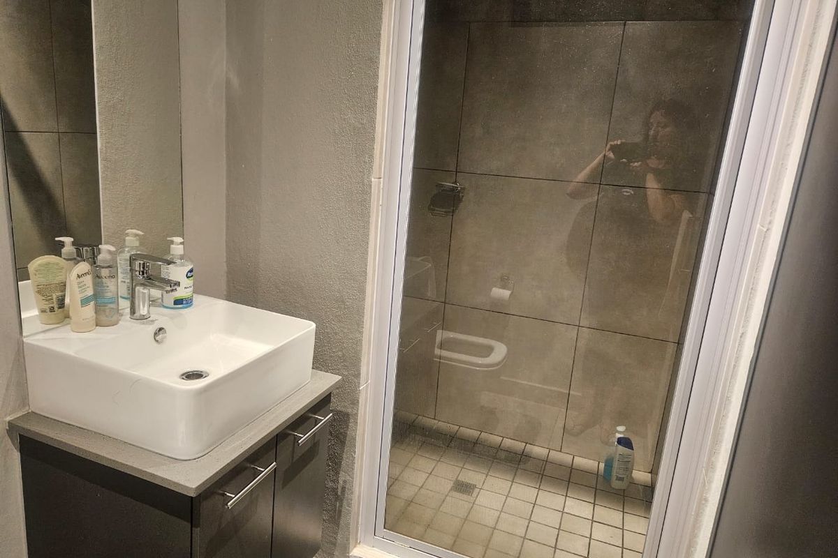 Modern bathroom featuring a vessel sink vanity, wall-mounted mirror, and a glass-enclosed shower with tiled finishes.