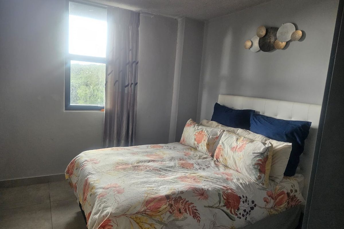 A standard bedroom featuring tiled flooring and an aluminium window frame, providing a functional space with neutral wall tones.