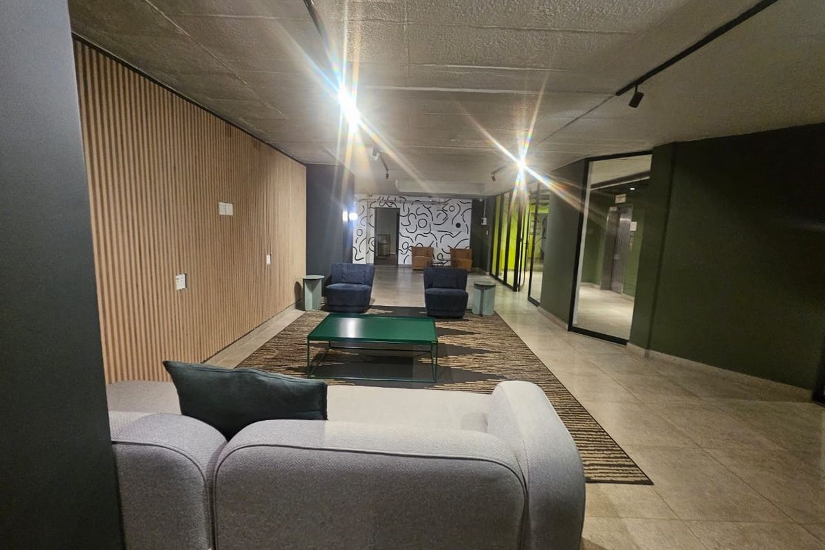Modern living area featuring contemporary timber slat wall paneling, exposed concrete ceilings, and sleek track lighting in a well-maintained apartment building.