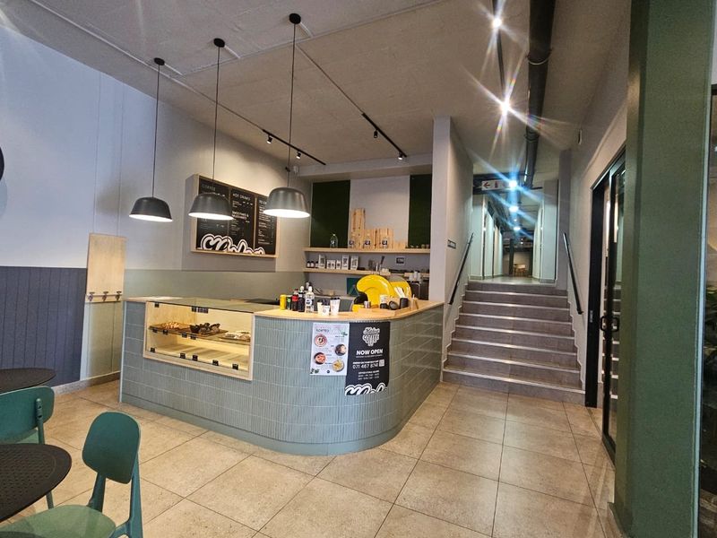 A commercial service area featuring a curved built-in counter, tiled flooring, and a staircase leading to an upper level.