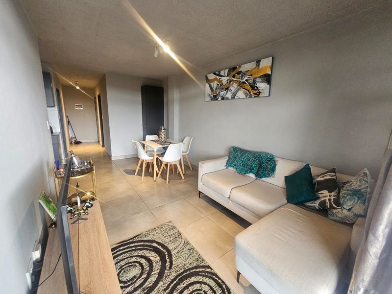 An open-plan living and dining area featuring neutral tiled flooring and neutral wall finishes, providing a functional space for relaxation and meals.