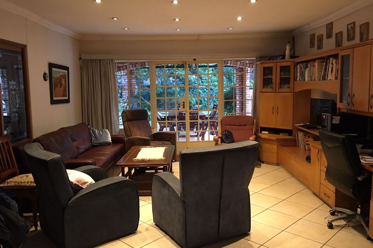 A comfortable living room featuring tiled flooring, recessed downlighting, and large glass-paned doors providing direct access to the outdoor patio area.