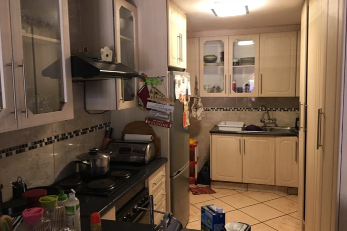 A functional kitchen featuring built-in cabinetry, a tiled backsplash, integrated stove and extractor fan, and a double sink setup.