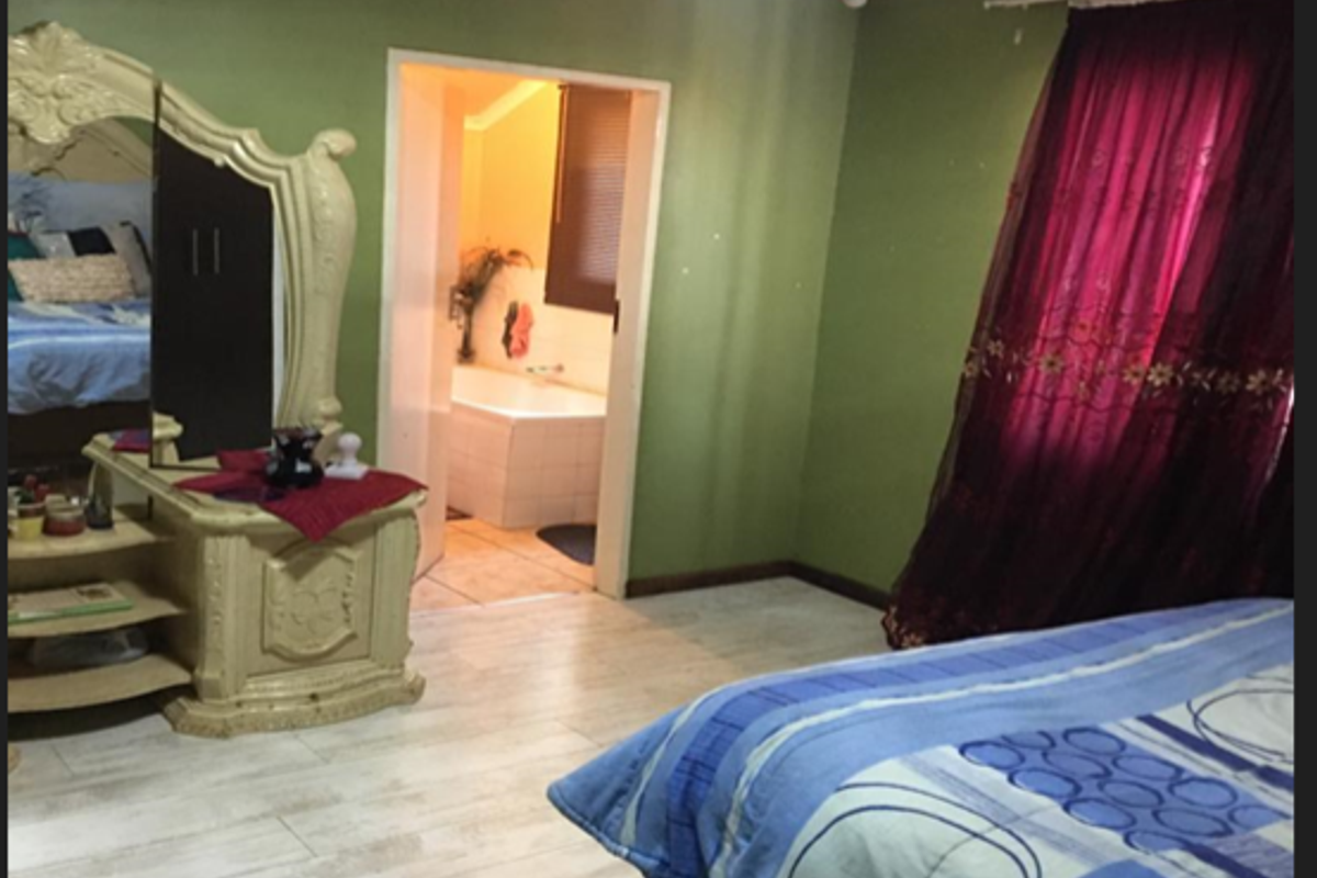 A bedroom featuring light-toned tiled flooring and an en-suite bathroom with a built-in bathtub.