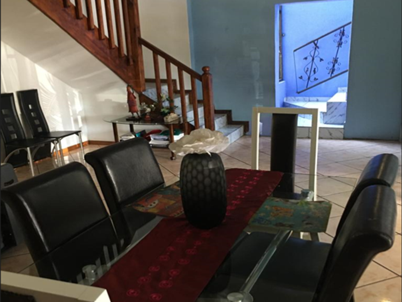 Open plan dining area featuring tiled flooring and a wooden staircase leading to the upper level.