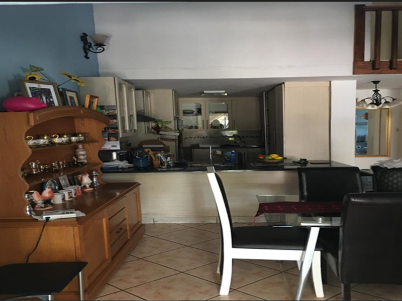 Open plan kitchen and dining area featuring built-in cabinetry, a breakfast counter, and tiled flooring.