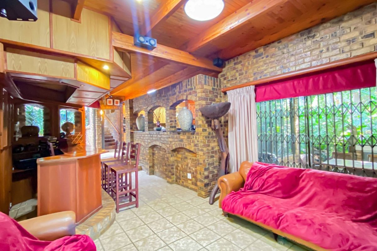 A rustic living area featuring exposed timber ceiling beams, face-brick walls, and a built-in bar counter, creating a warm, traditional entertainment space.
