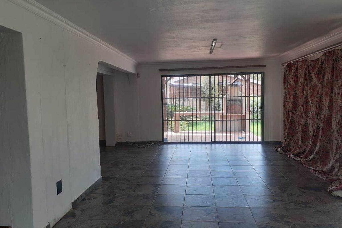Spacious living area featuring dark tiled flooring and large sliding glass doors with security bars, providing direct access to the rear patio and garden.