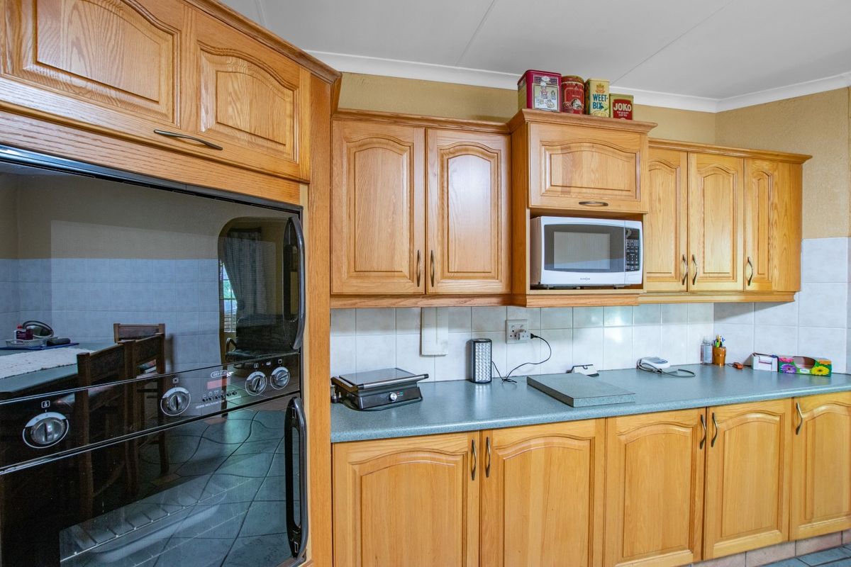 A functional kitchen featuring traditional oak-finish cabinetry, tiled splashbacks, and a built-in eye-level oven, offering a classic and practical workspace.