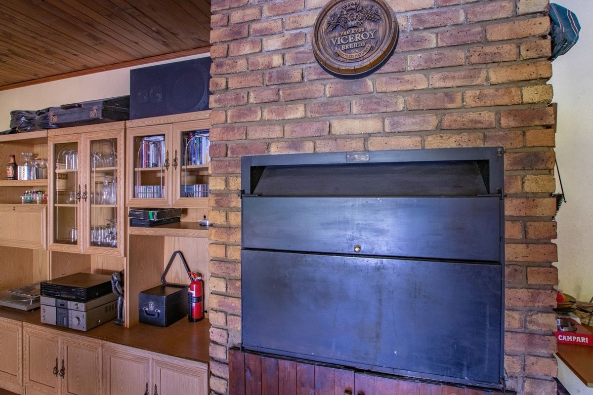 A living room featuring a prominent face-brick fireplace with a built-in metal hearth and integrated wooden cabinetry for storage and display.