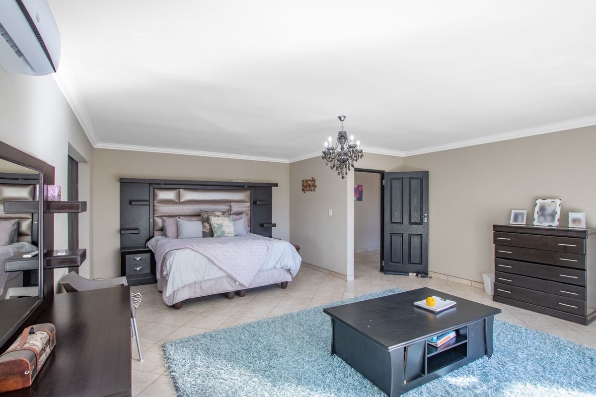 Spacious bedroom featuring tiled flooring, crown molding, and a wall-mounted air conditioning unit.