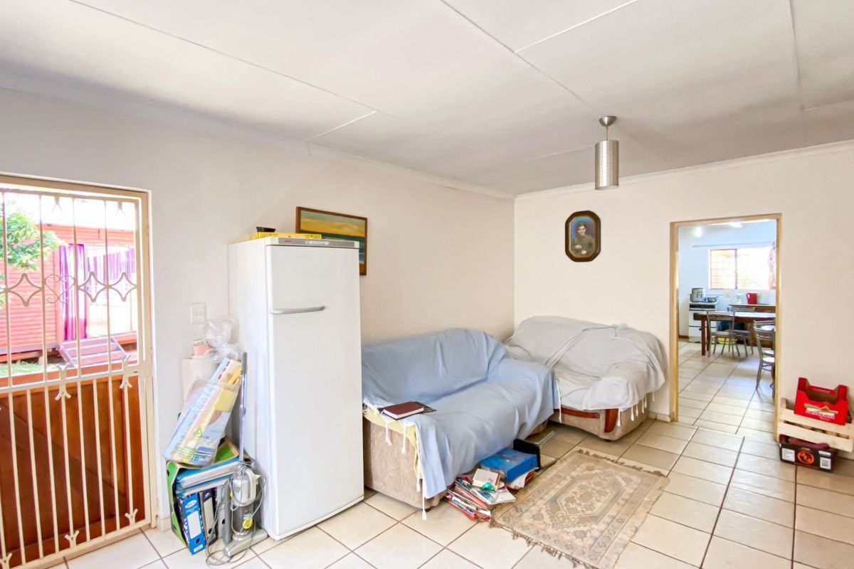 A living area featuring ceramic floor tiles, a security gate leading to the exterior, and an open transition into the adjacent kitchen space.