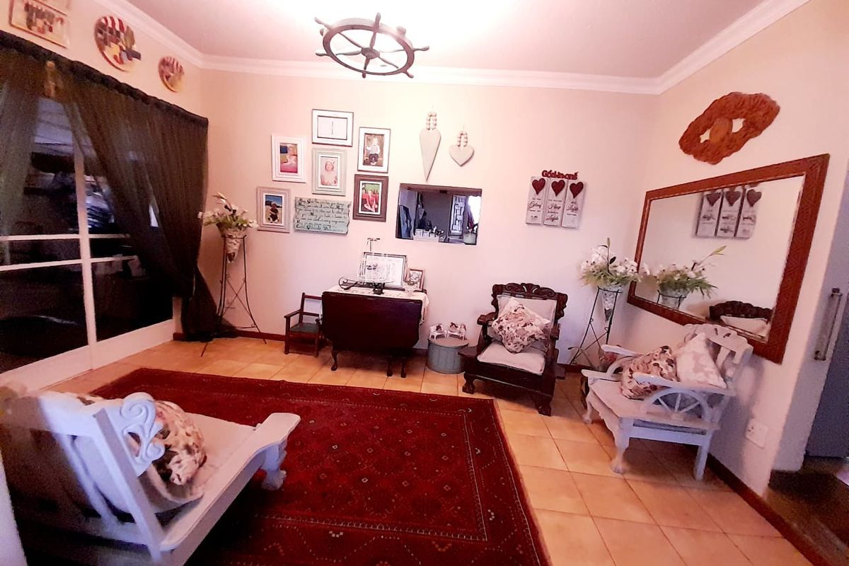 A living room featuring tiled flooring, crown molding, and a large wall-mounted mirror, providing a comfortable and well-defined space for relaxation.