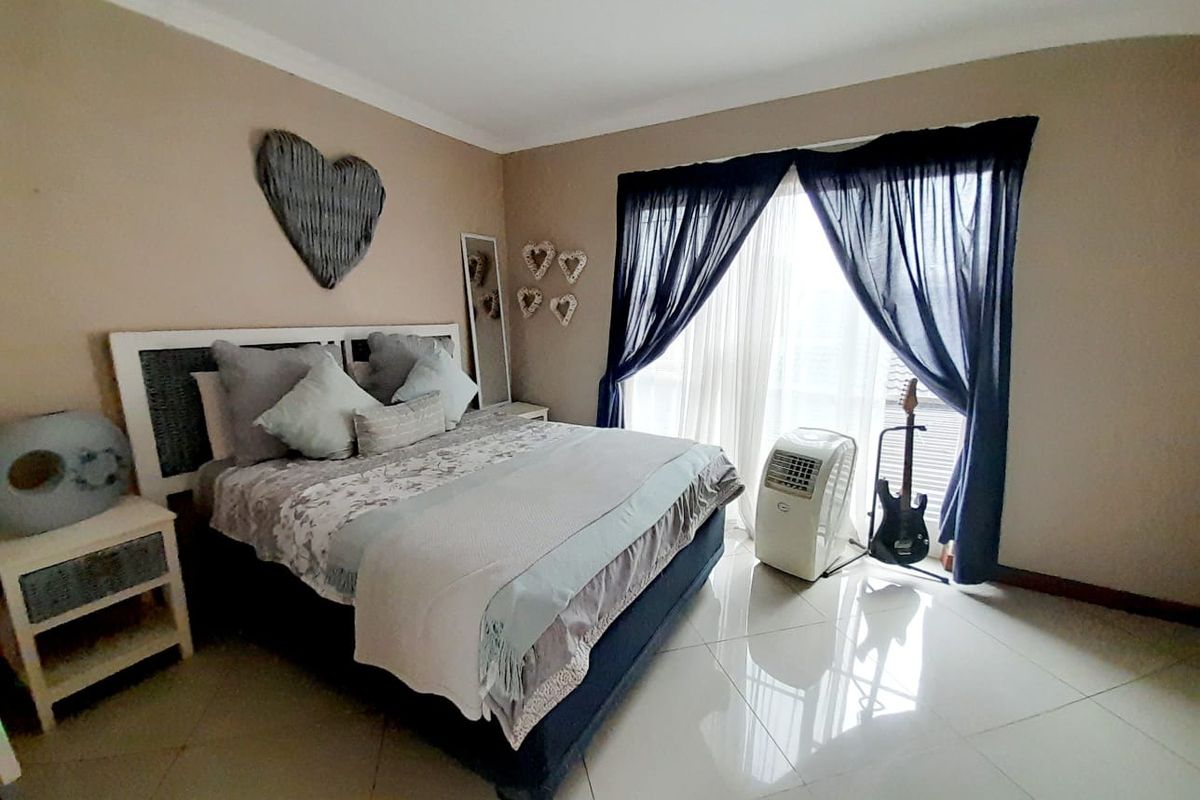 A well-lit bedroom featuring large format floor tiles, neutral wall tones, and a sliding door providing access to the exterior.