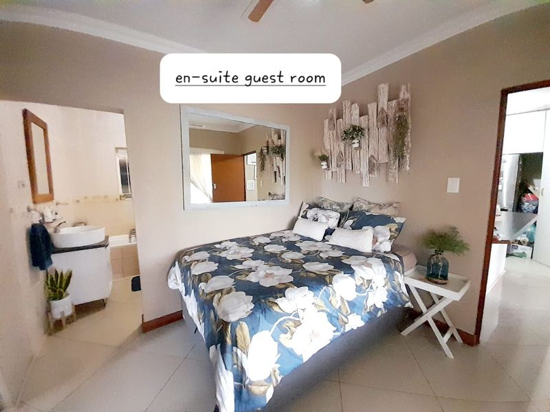 A bedroom featuring an en-suite bathroom with a vanity and tiled flooring, offering a functional layout for guests.