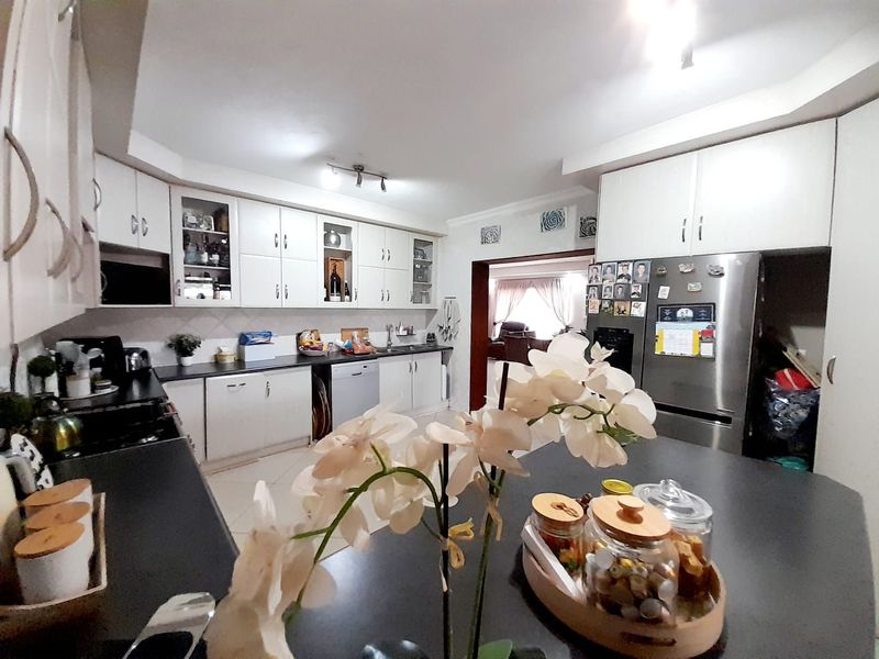 A functional kitchen featuring white cabinetry, dark countertops, and an integrated layout with a central island, providing ample storage and workspace.