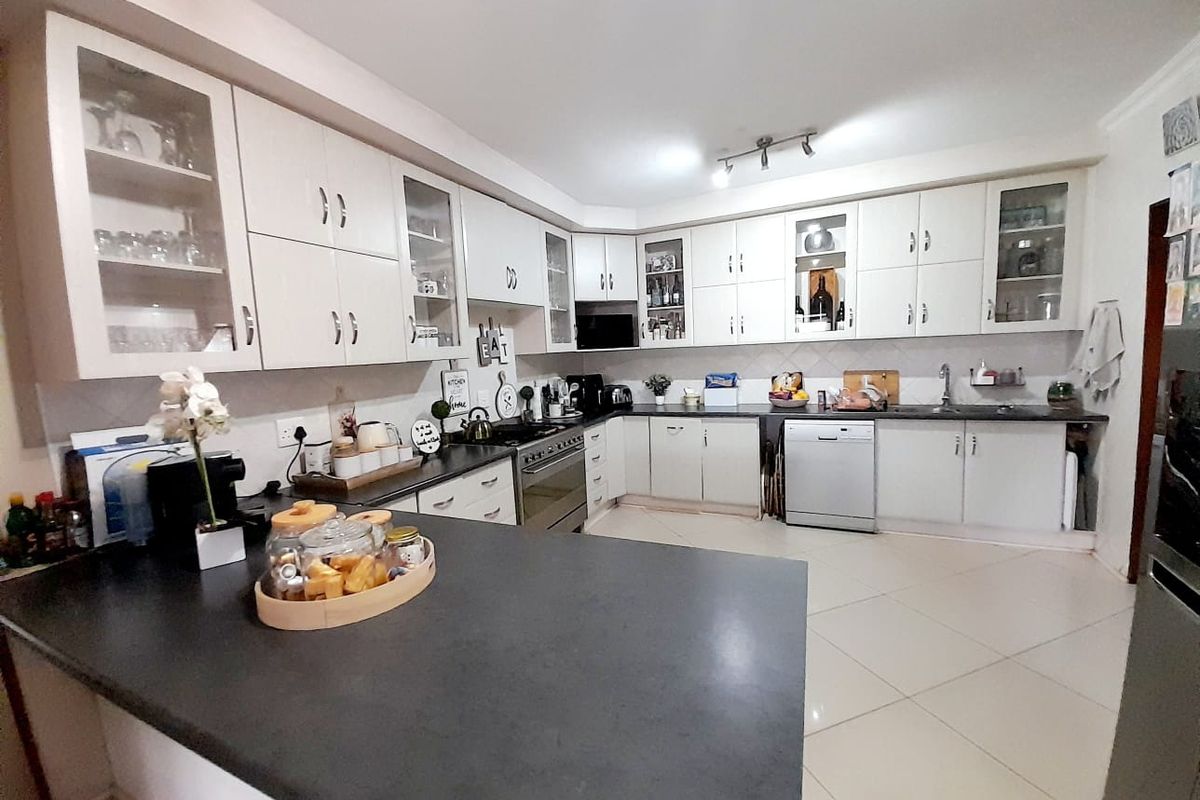 A well-maintained kitchen featuring white cabinetry, dark countertops, a built-in oven with gas hob, and tiled flooring.