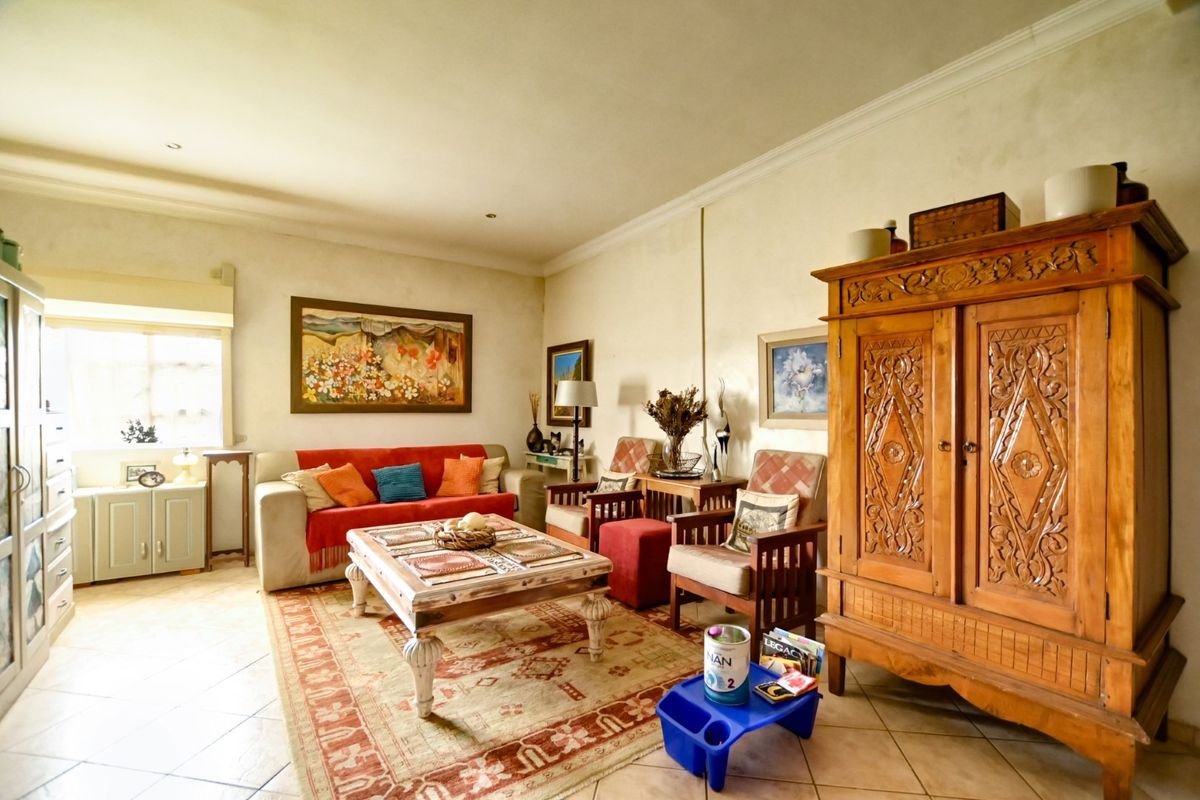 A spacious living room featuring tiled flooring, recessed downlighting, and decorative cornicing, providing a comfortable and well-lit area for relaxation.