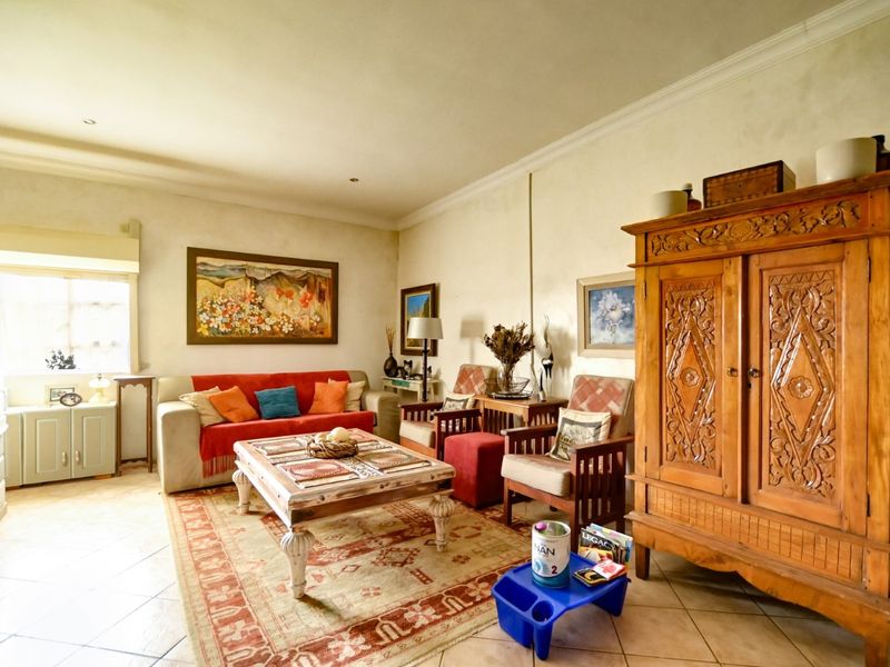 A spacious living room featuring tiled flooring, recessed downlighting, and decorative cornicing, providing a comfortable and well-lit area for relaxation.