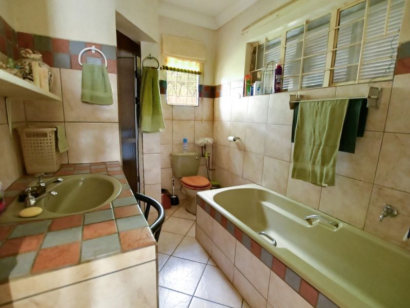 A dated bathroom featuring a built-in bathtub, tiled vanity with integrated basin, and ceramic wall and floor tiling throughout.