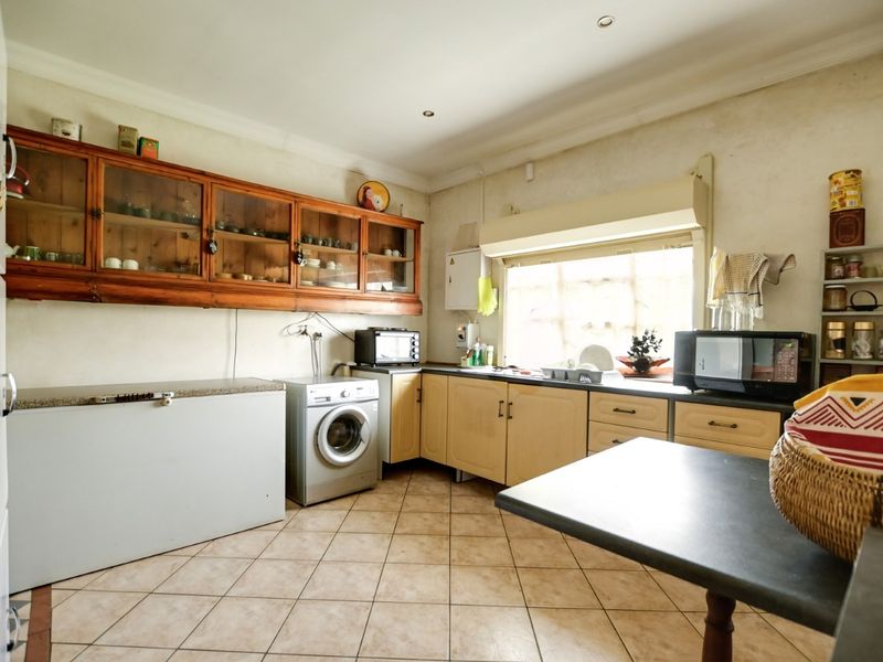 A functional kitchen featuring built-in wooden cabinetry, tiled flooring, and laminate countertops, offering a practical layout with potential for cosmetic updates.