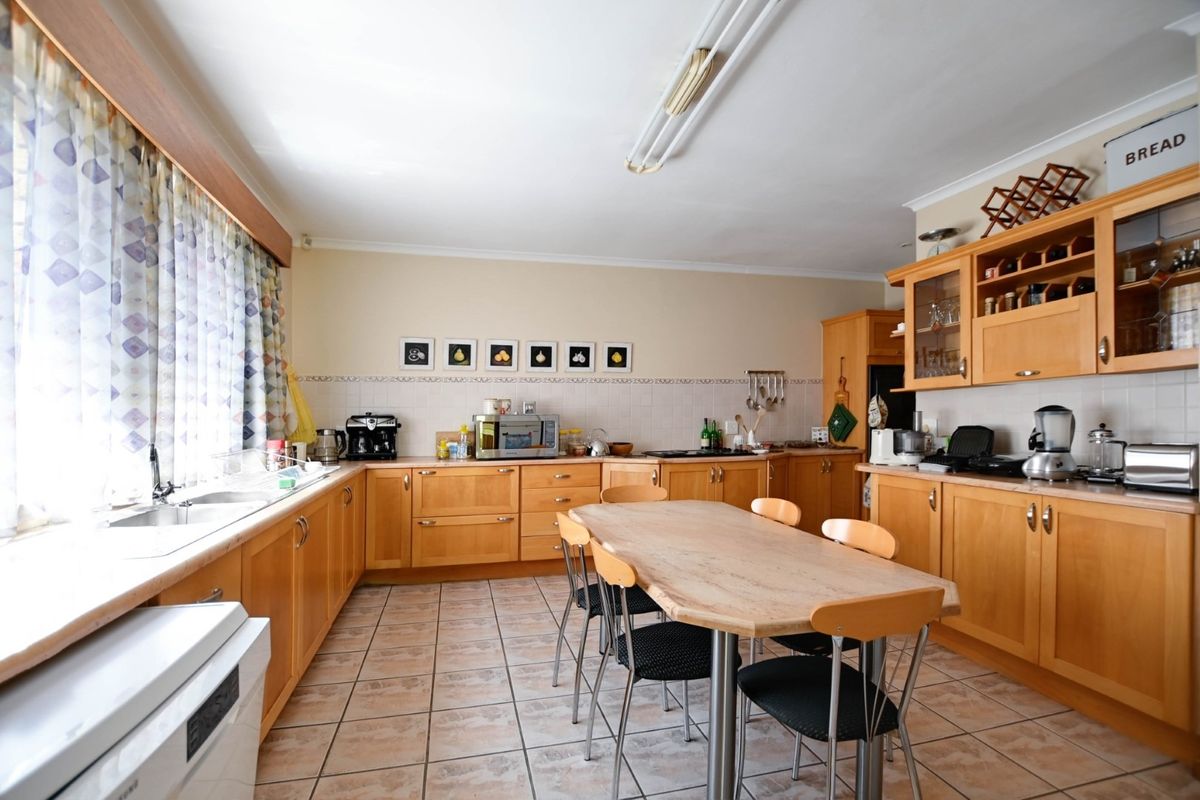 Spacious kitchen featuring light wood cabinetry, tiled flooring, and a dedicated dining area, offering a functional layout with ample storage space.