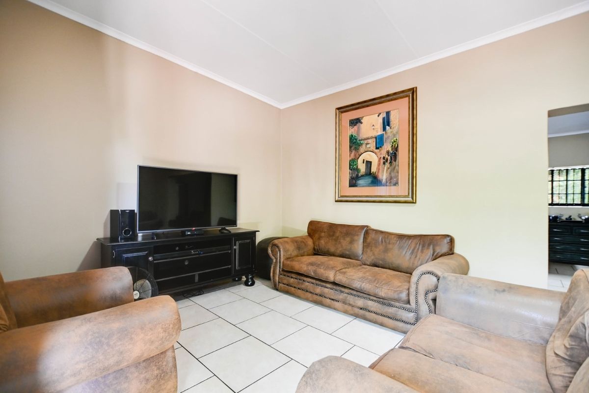 A comfortable living room featuring neutral wall tones and light-colored floor tiles, providing a functional and inviting space for relaxation.