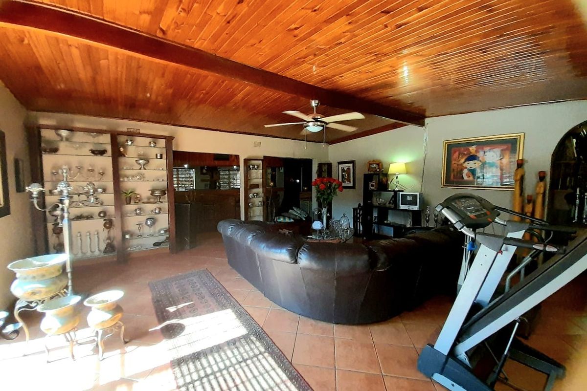 Spacious living area featuring a high timber-clad vaulted ceiling with exposed beams, tiled flooring, and built-in display cabinetry.
