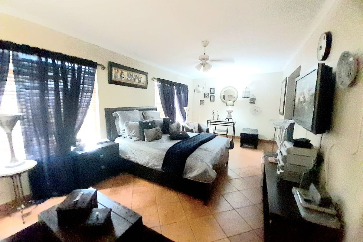 Spacious bedroom featuring tiled flooring, a ceiling fan, and large windows allowing for natural light.