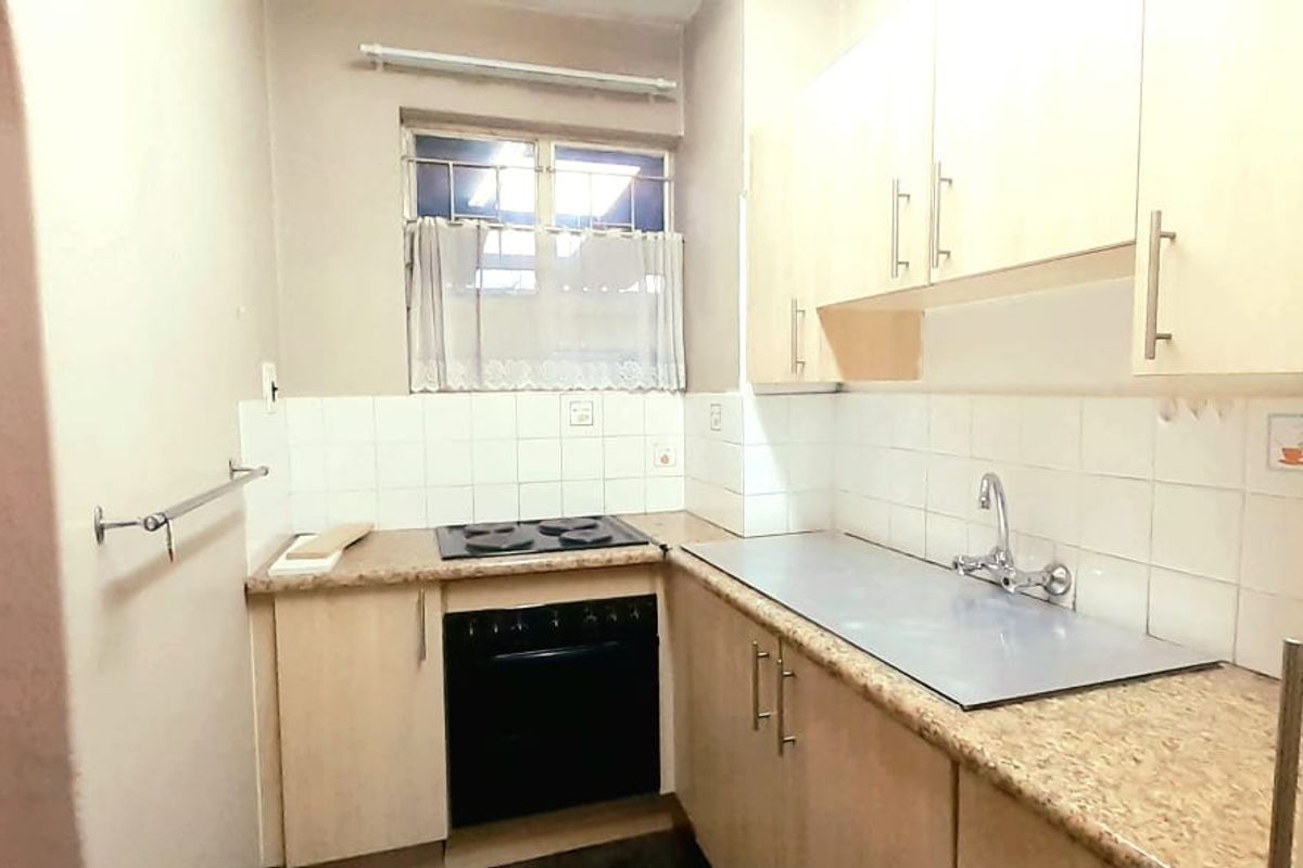 Compact kitchen featuring built-in cabinetry, laminate countertops, a fitted electric oven and hob, and a tiled splashback.